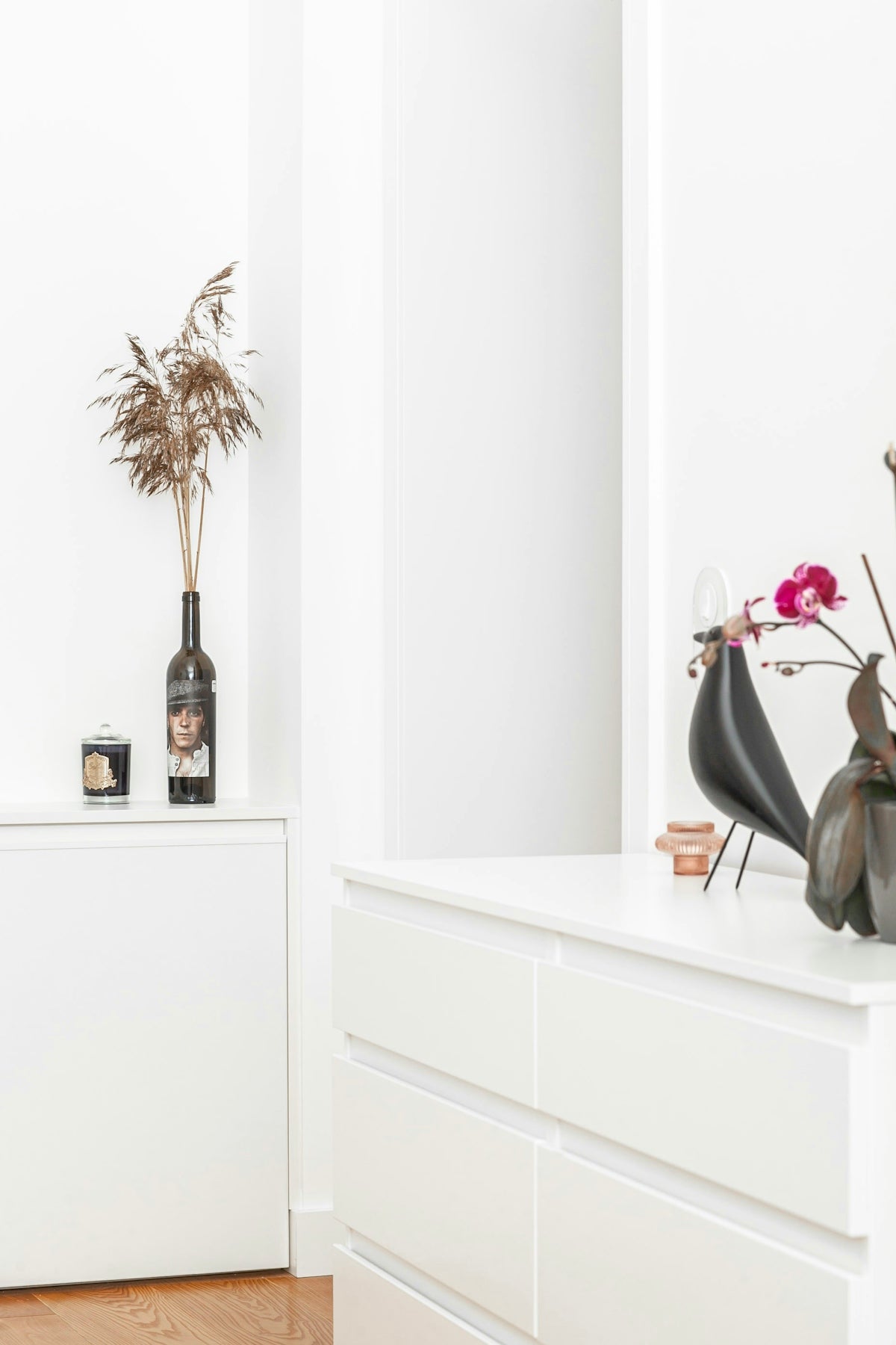 a white dresser with a vase of flowers on top of it