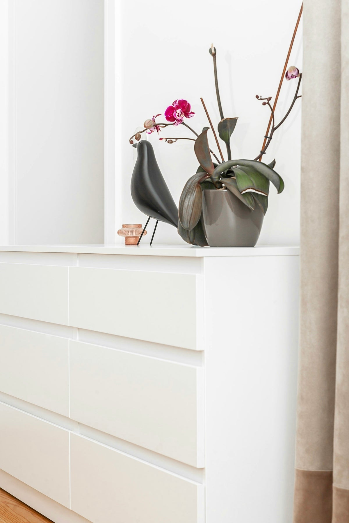 a white dresser with a vase of flowers on top of it