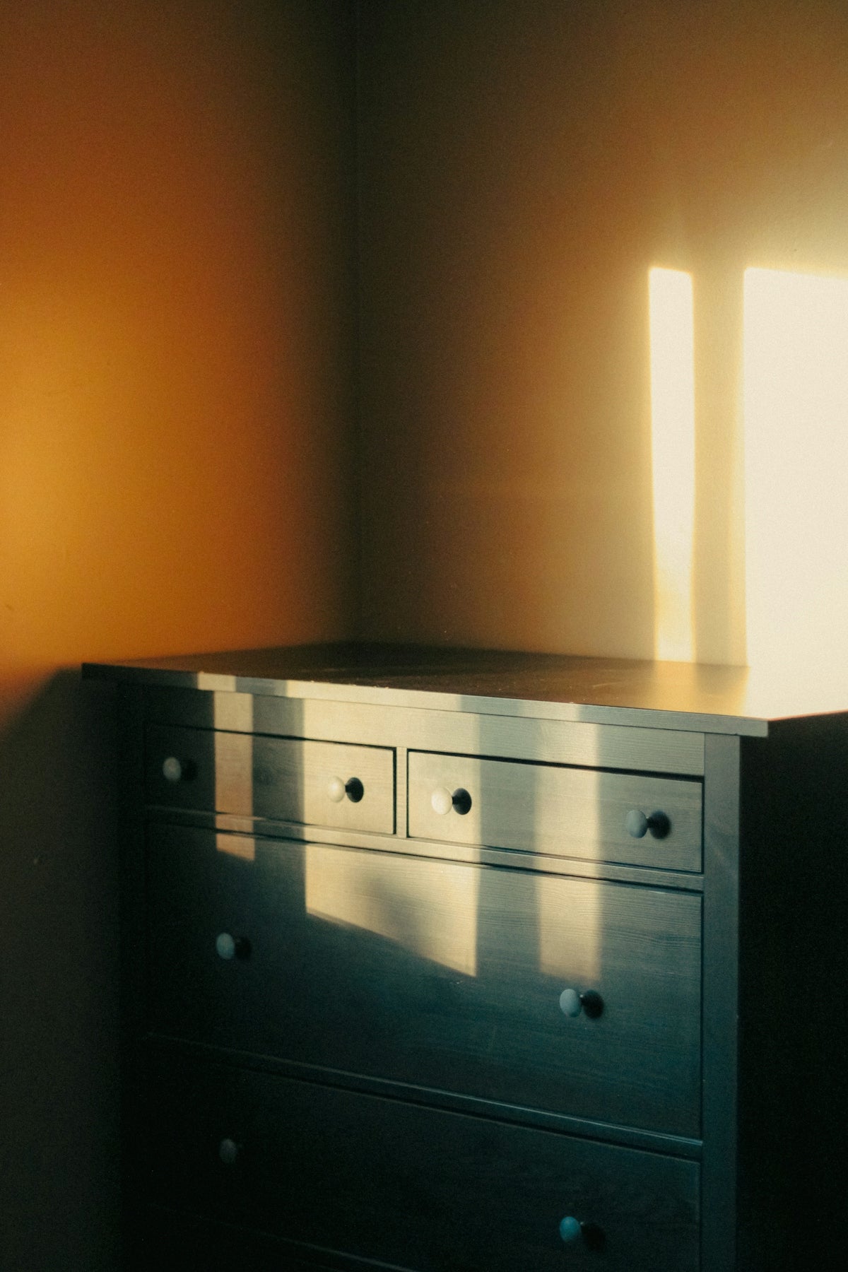 an empty room with a dresser and a window