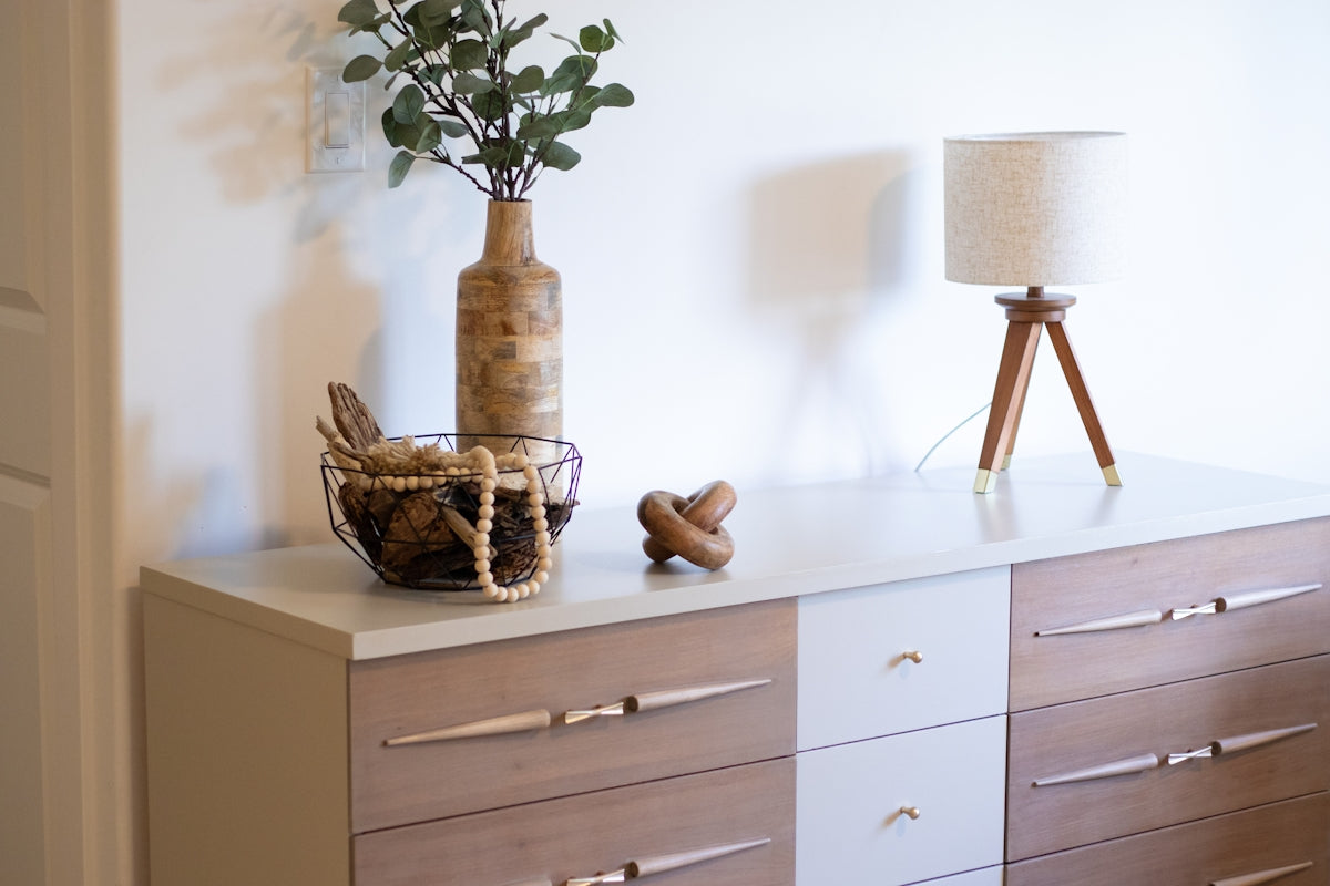 A vase with a plant on top of a dresser