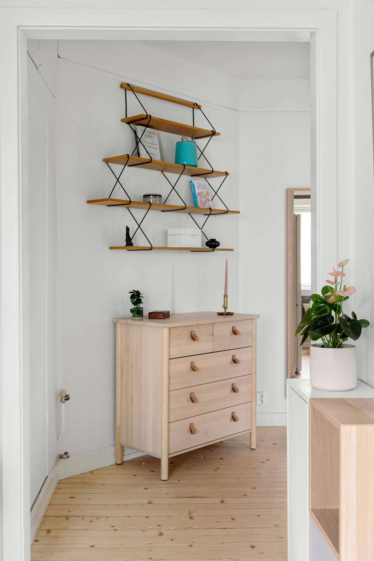 A white room with a wooden dresser and shelves
