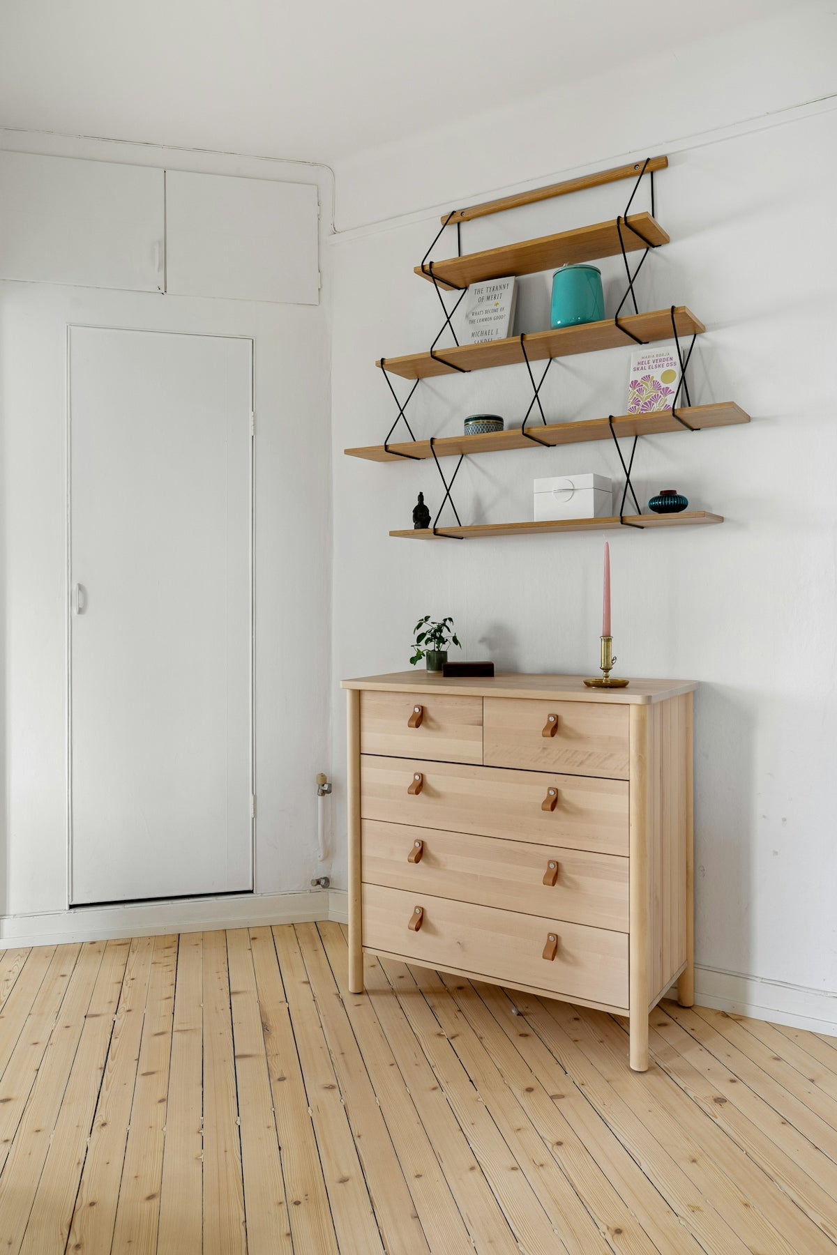 A white room with a wooden dresser and shelves