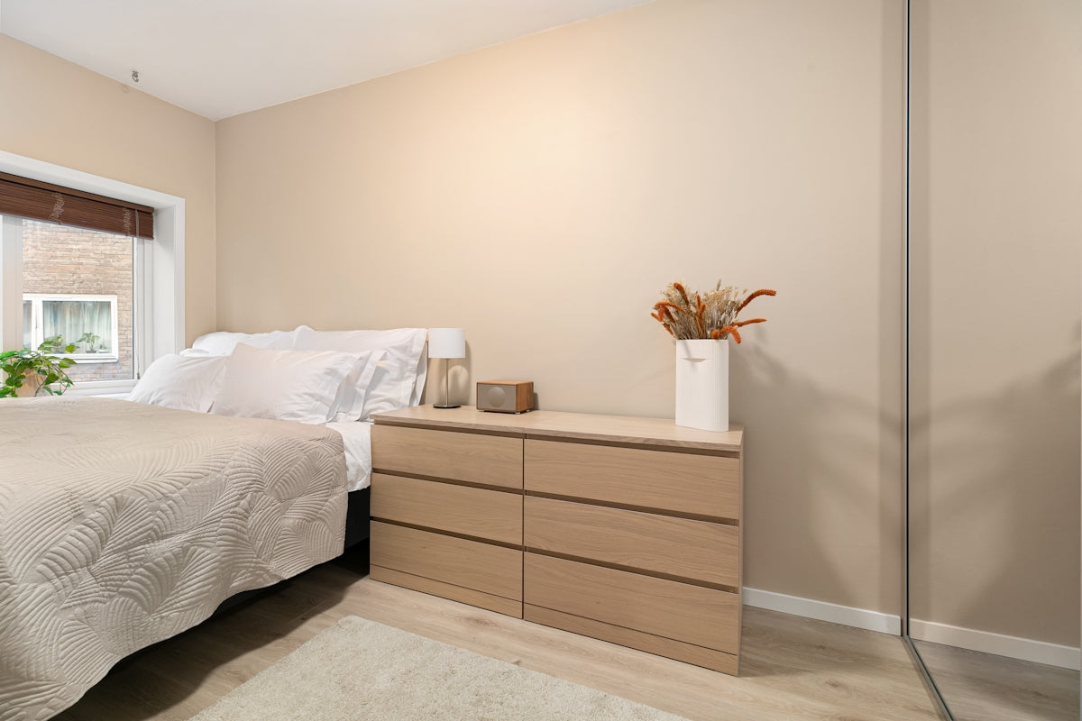 A bedroom with a bed, dresser, and window