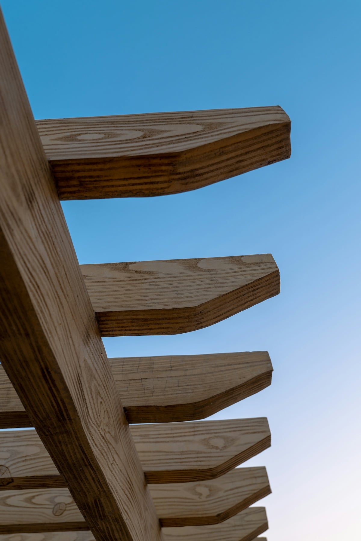 A close up of a wooden bench against a blue sky