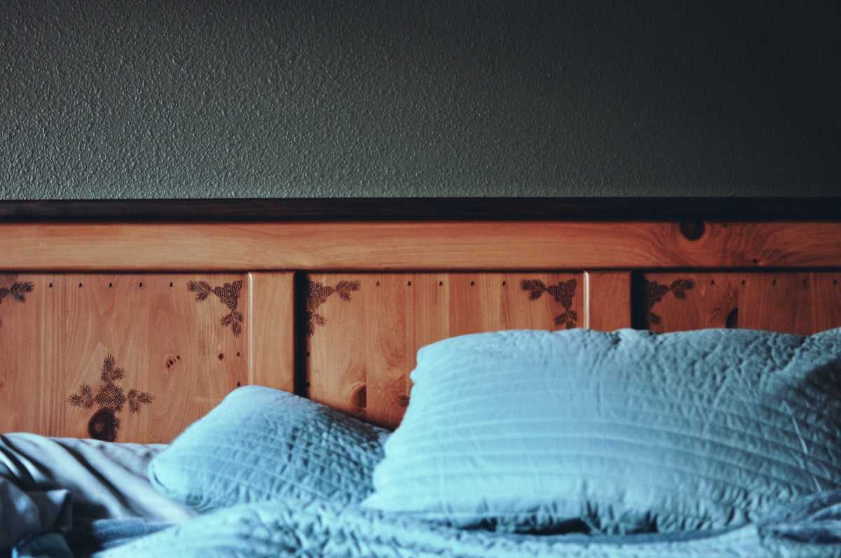 A bed with a blue comforter and pillows