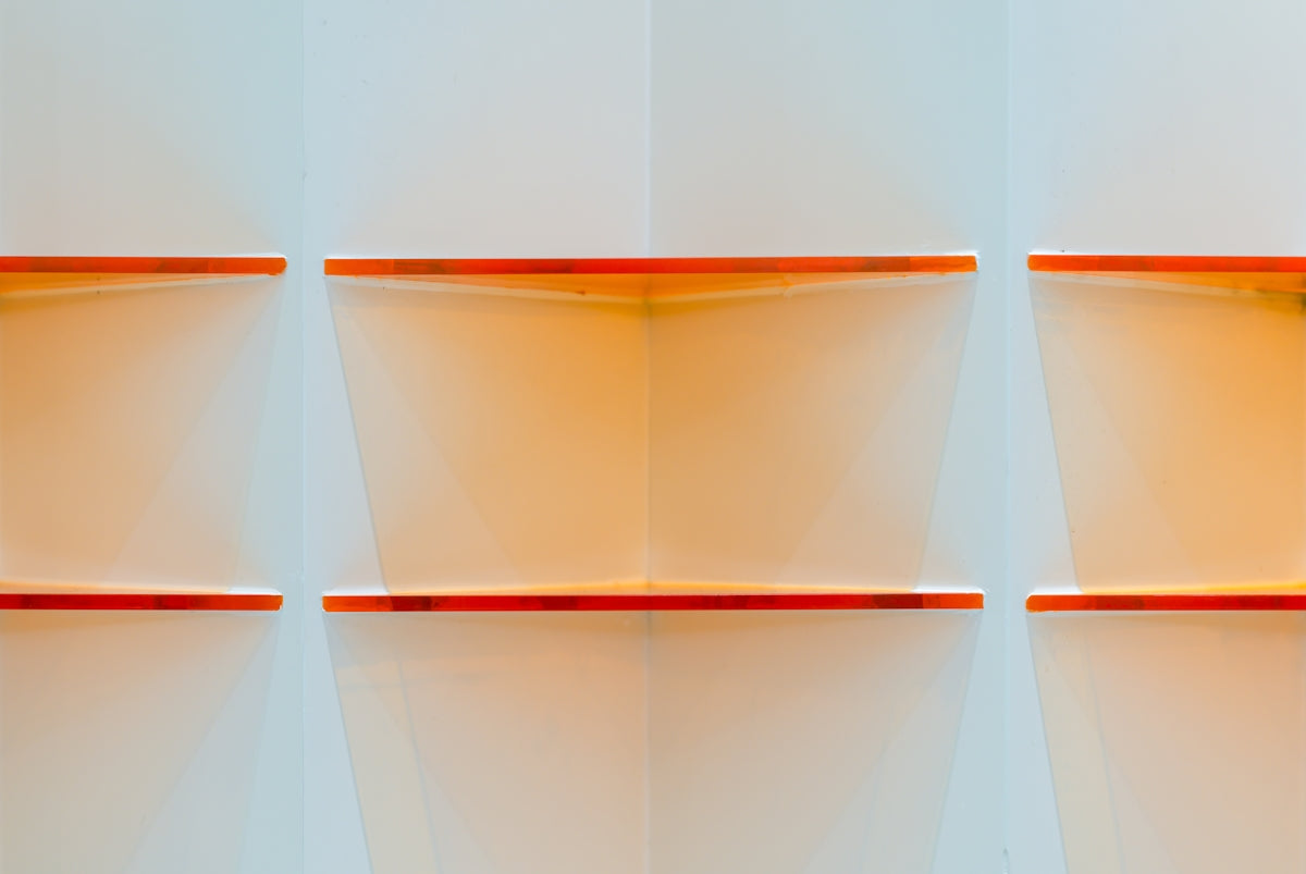 A white wall with orange shelves on it
