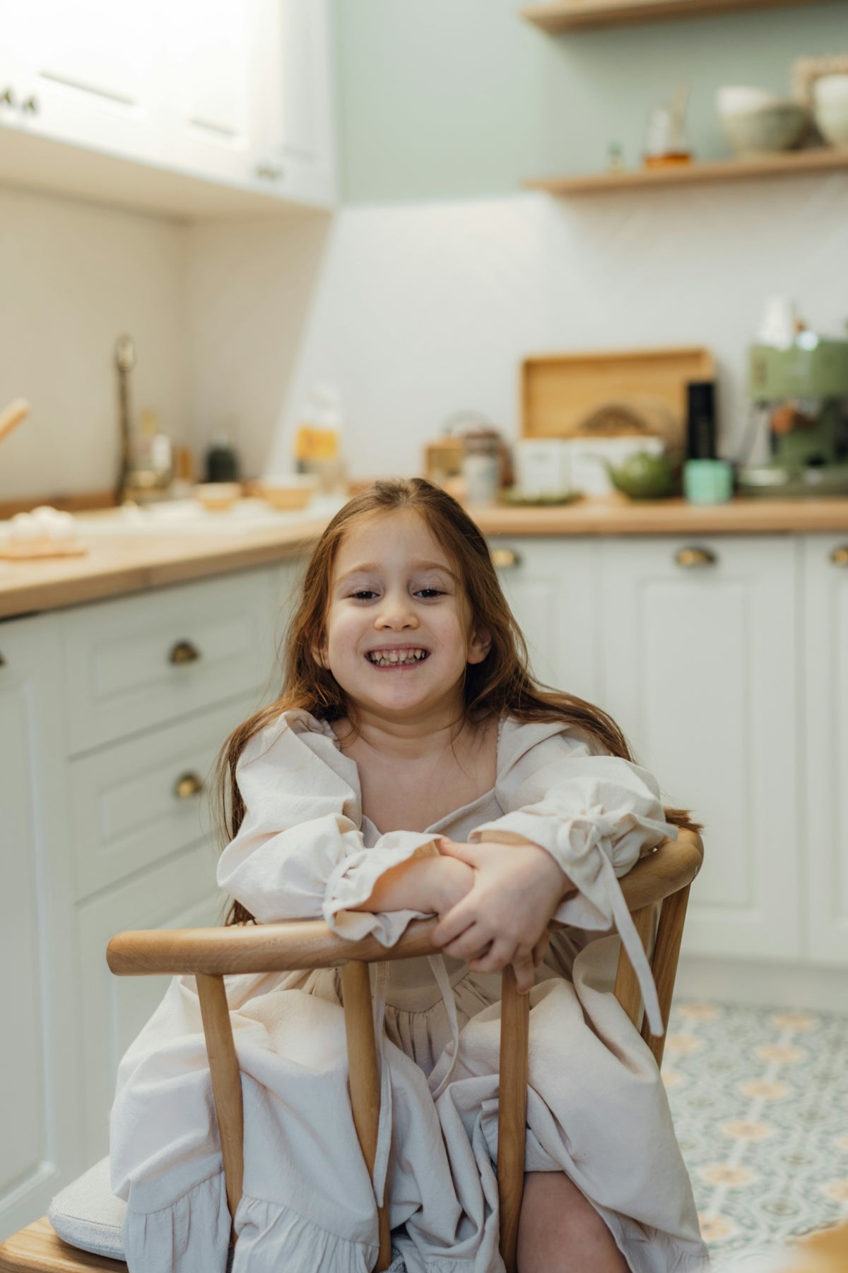 A little girl sitting in a chair in a kitchen
