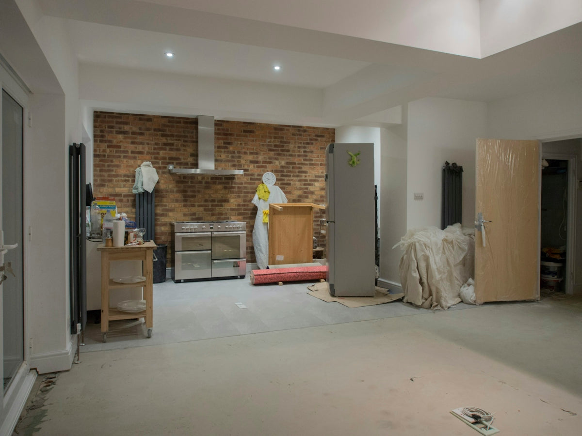 An unfinished kitchen with exposed brick and appliances.