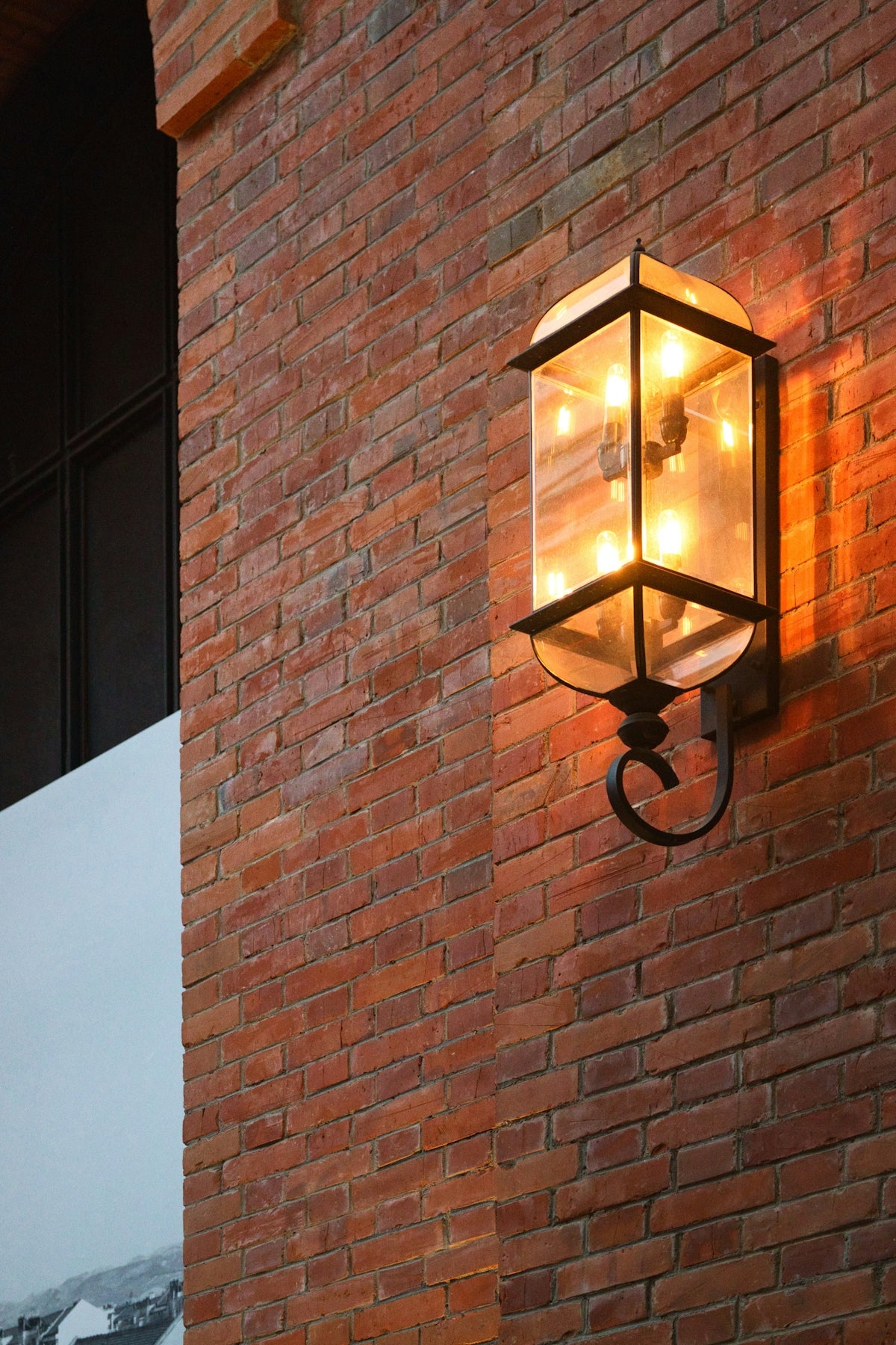 A brick wall and a lit exterior lamp.