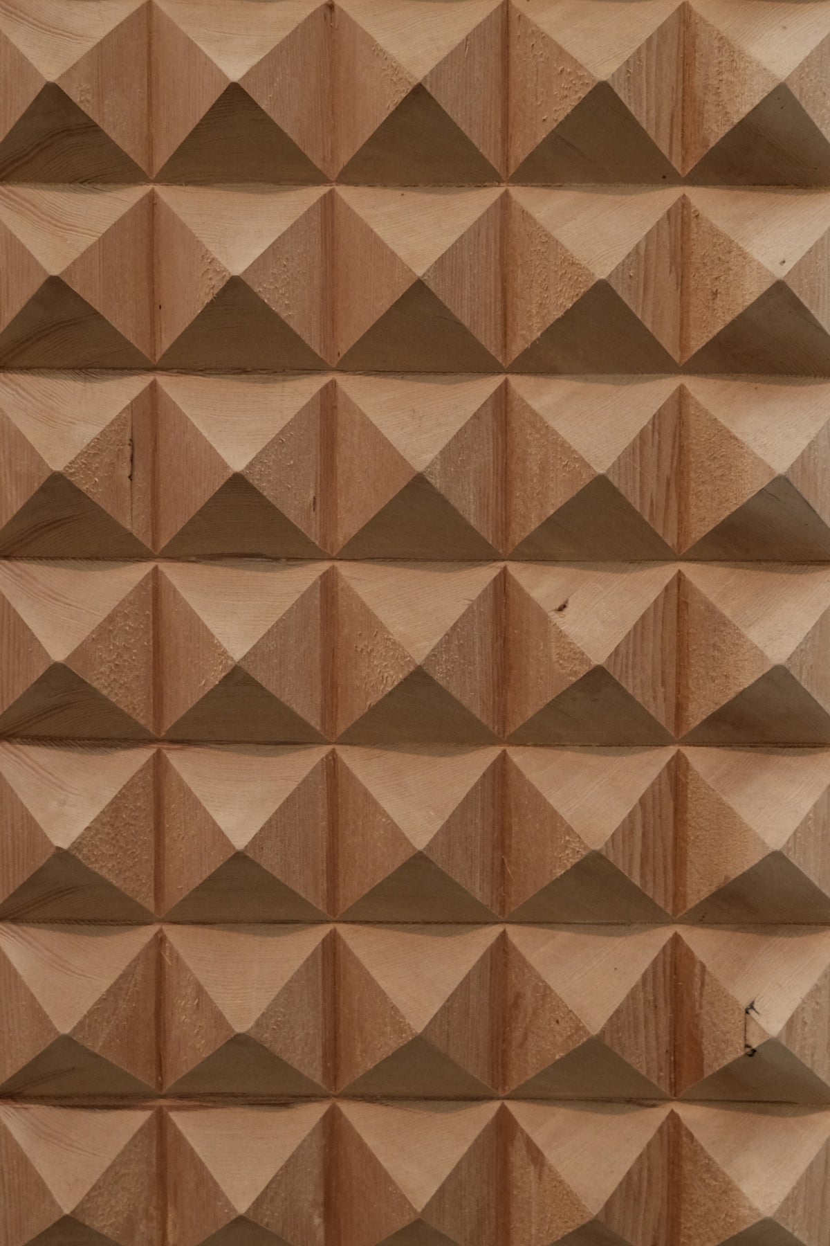 Pyramid-shaped wood carving creates a patterned surface.
