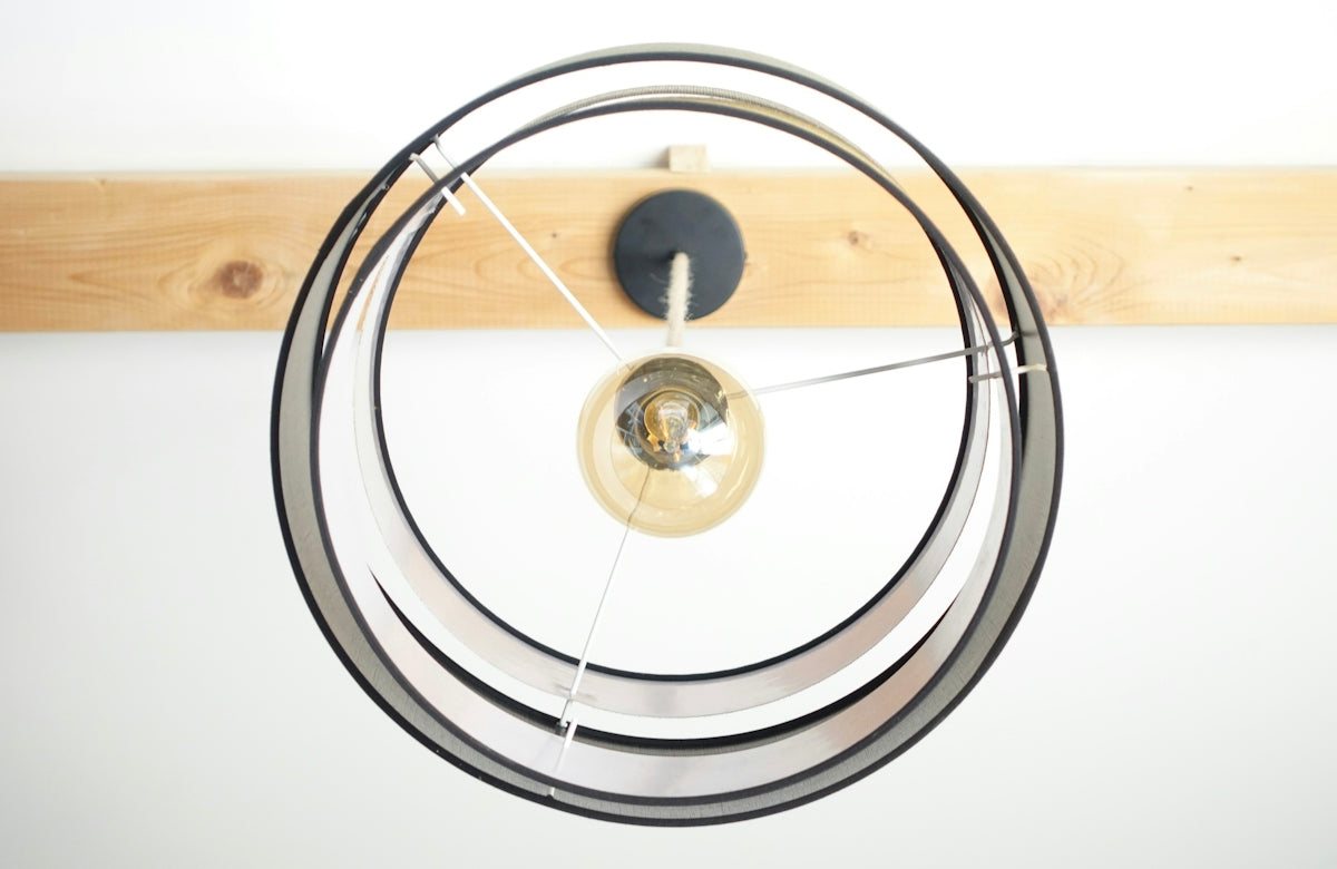 A modern lamp hangs from a wooden beam.