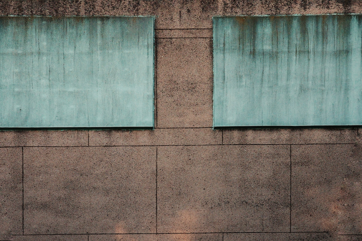Two square, weathered panels on a textured wall.