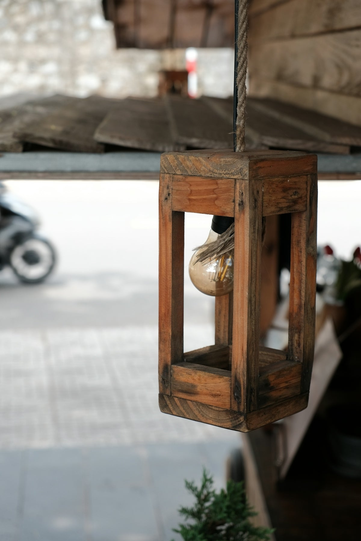Wooden lantern with light bulb hanging outdoors
