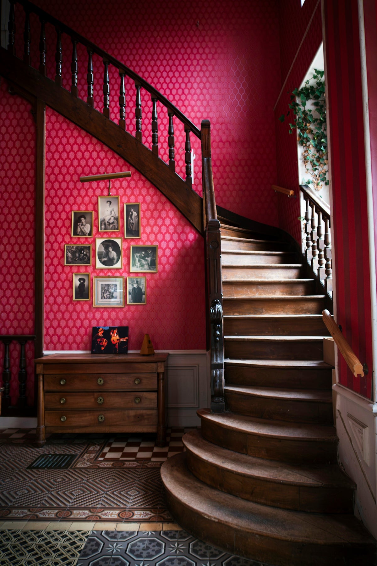 Wooden staircase with framed photos on pink wallpaper