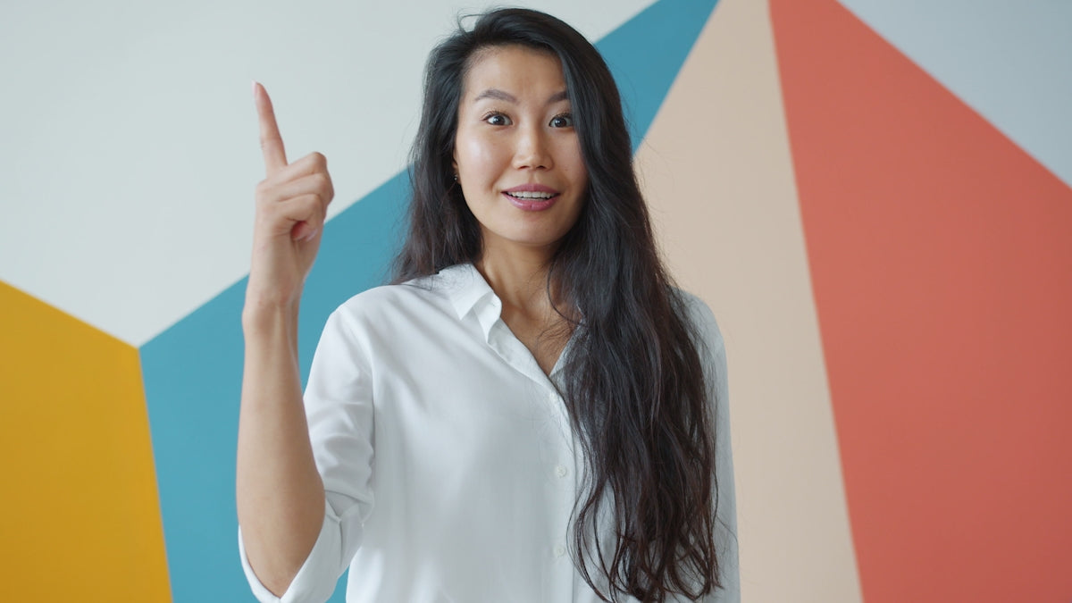 Young woman points finger upwards with idea