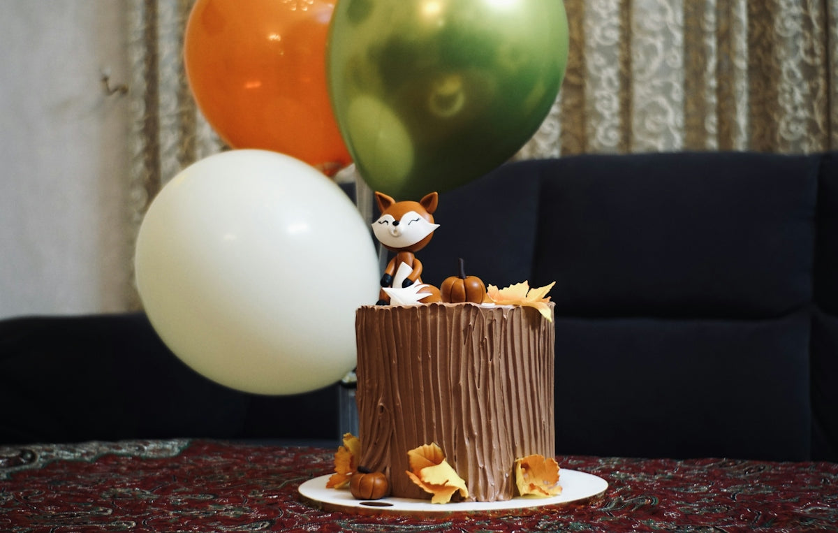 Tree stump cake with fox decoration and balloons