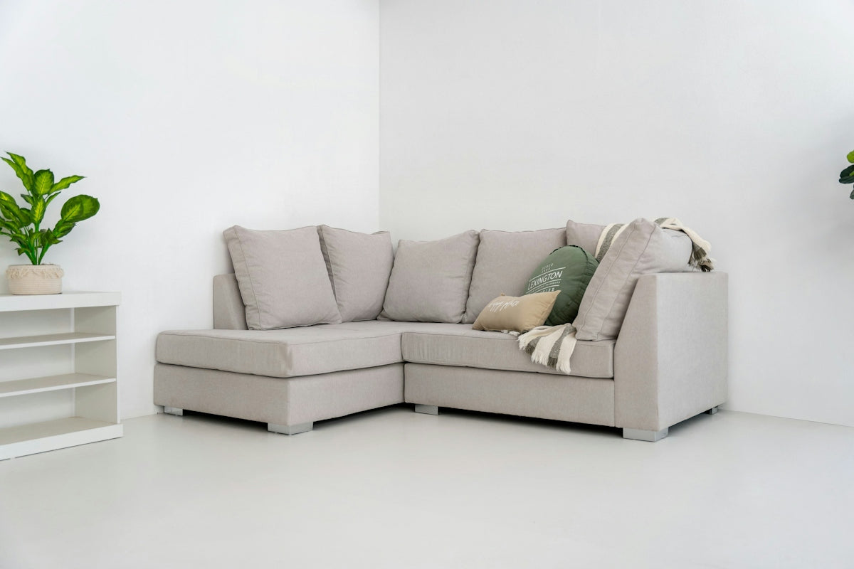 A light gray sectional sofa with pillows and blanket.