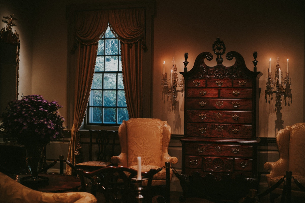 Antique room with chest, chairs, and candles.