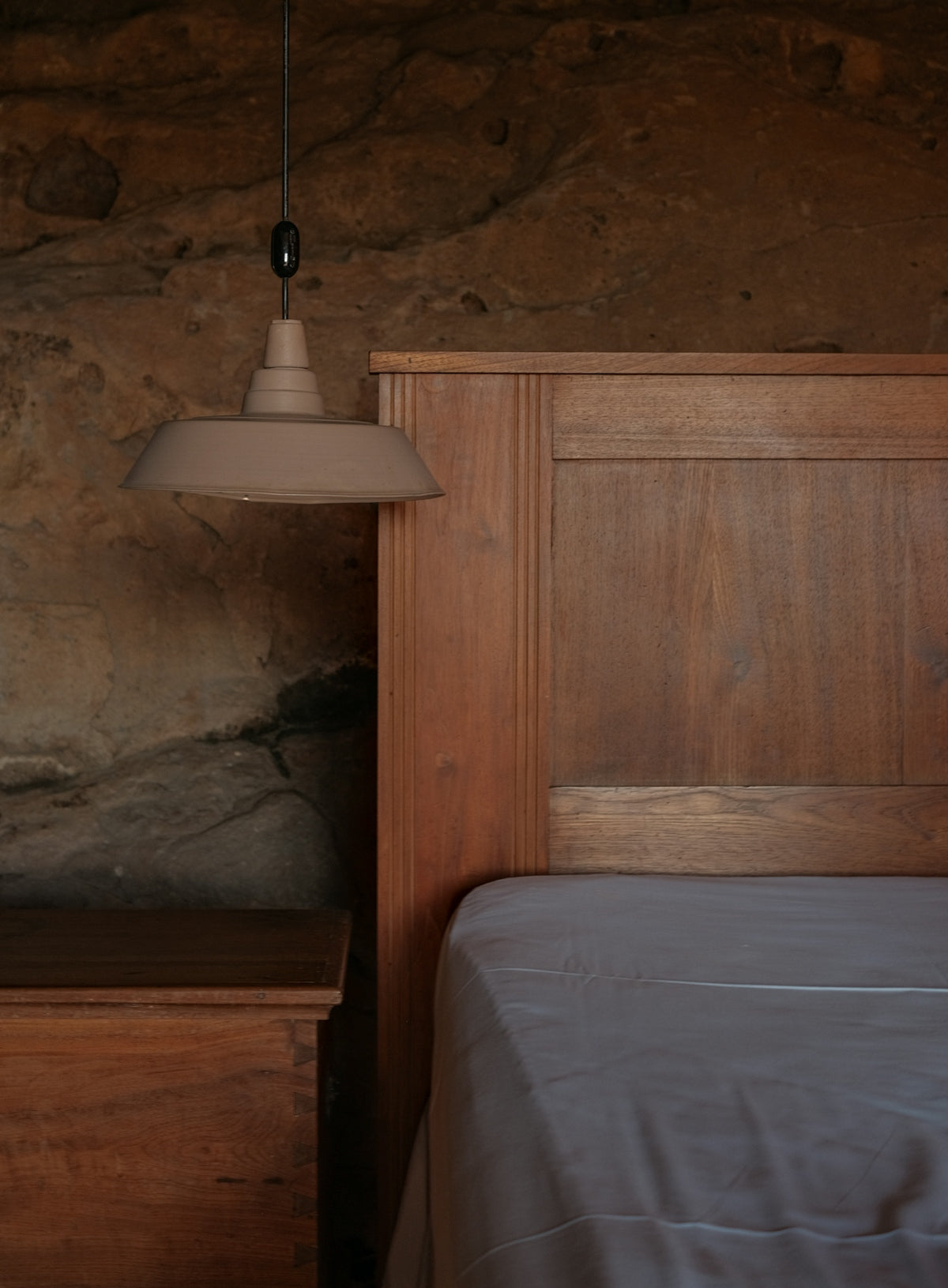 Wooden headboard and bedside table with lamp.