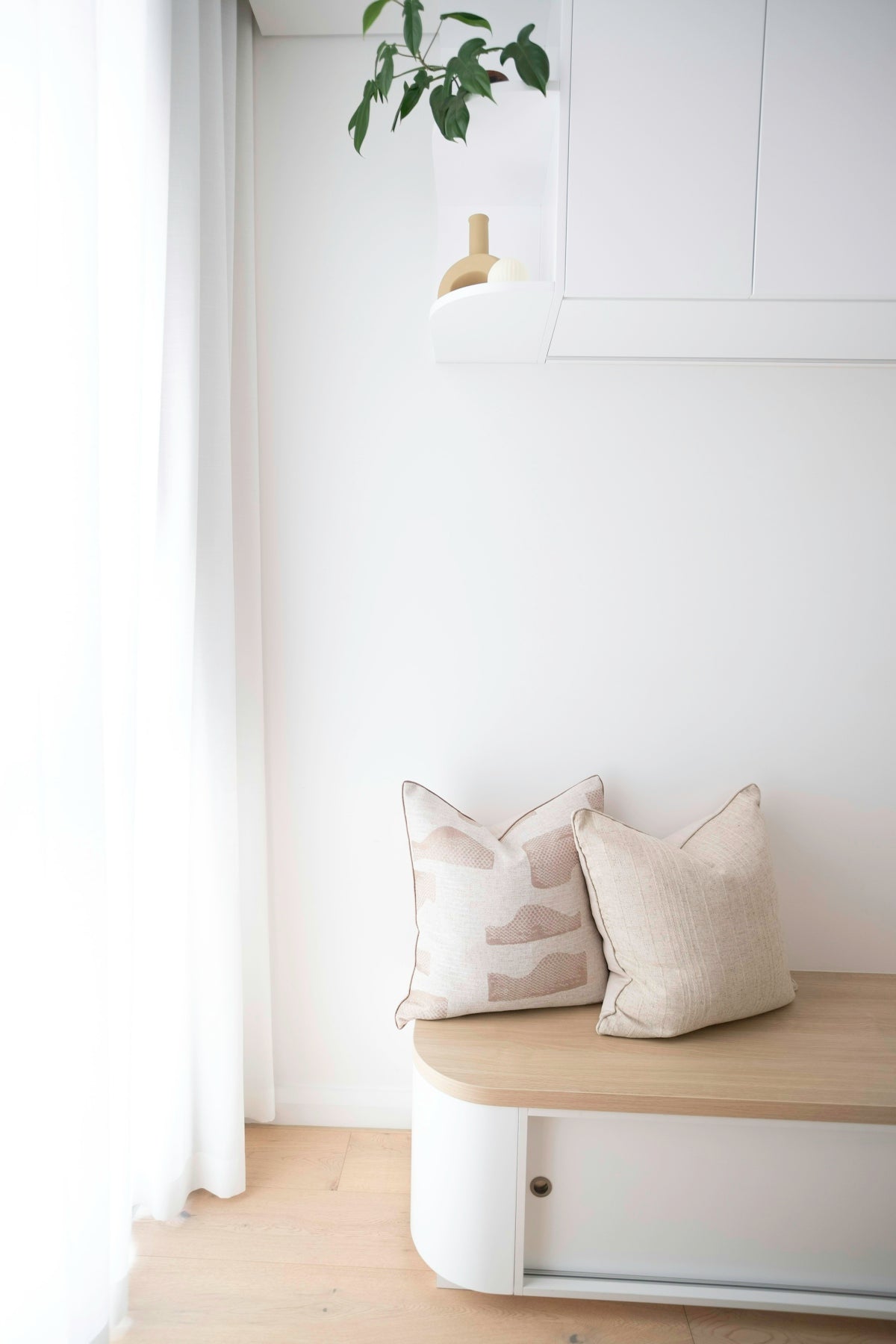 Two decorative pillows on a modern wooden bench.
