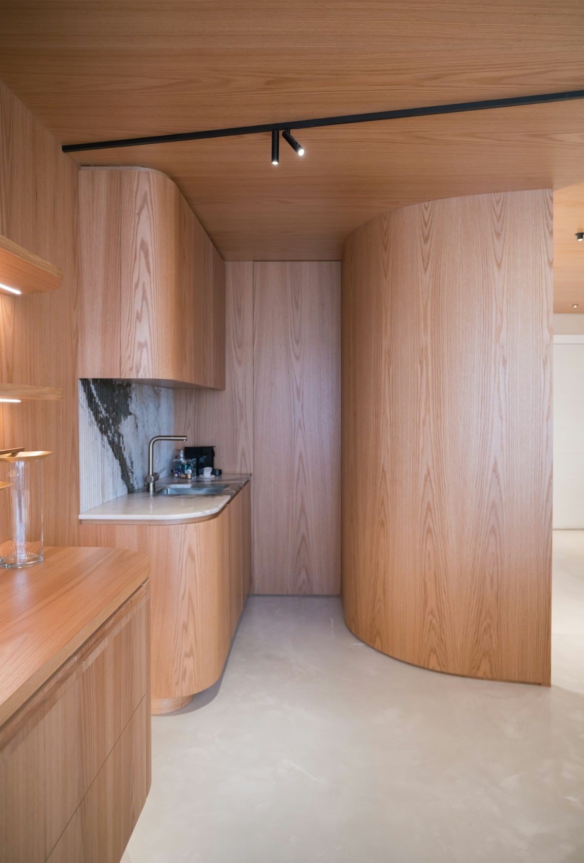 Modern kitchen with curved wooden cabinets and marble backsplash