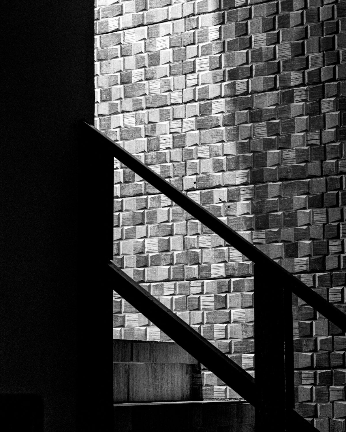 Shadows on a textured wall with a railing.