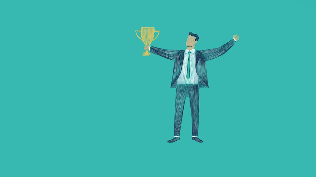 Man in suit holding a trophy with arms raised