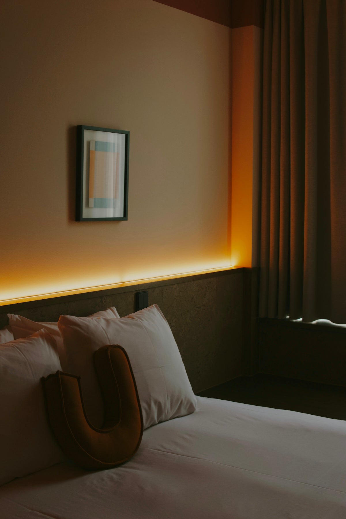 A hotel bed with pillows and ambient lighting.