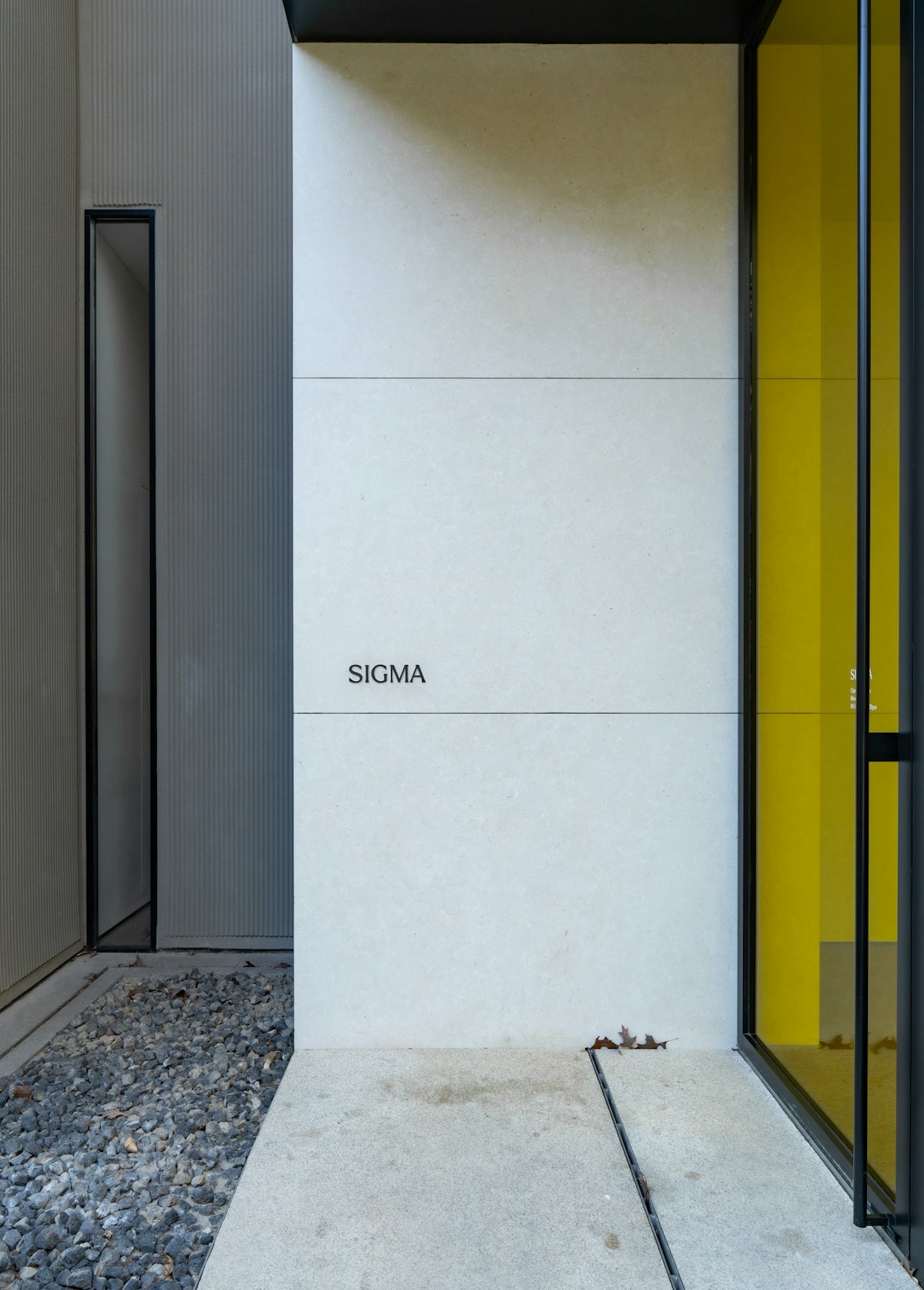 Modern building entrance with yellow accents and gravel.