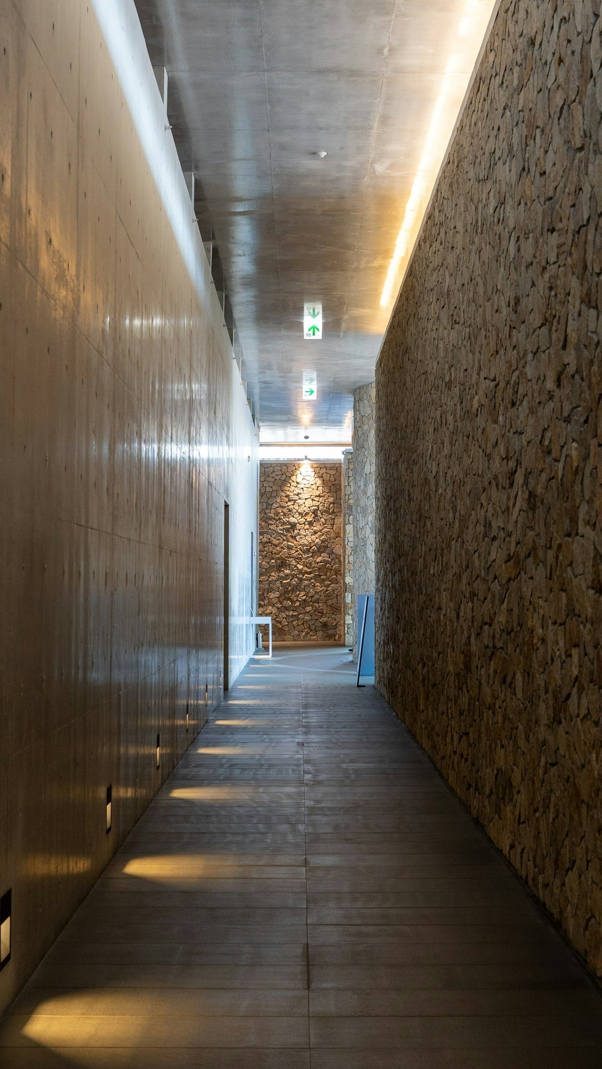 Modern hallway with textured stone and concrete walls.