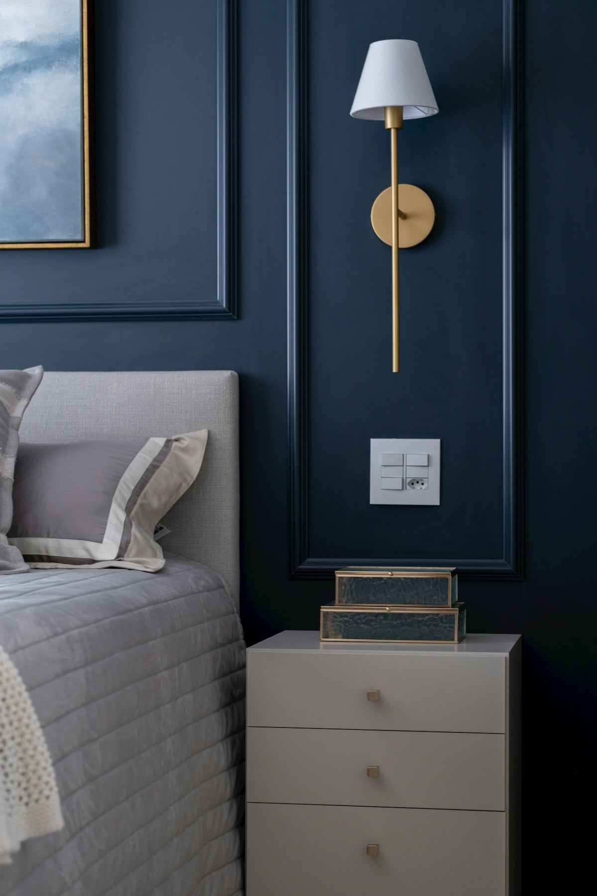 Elegant bedroom with a gold wall sconce and nightstand.