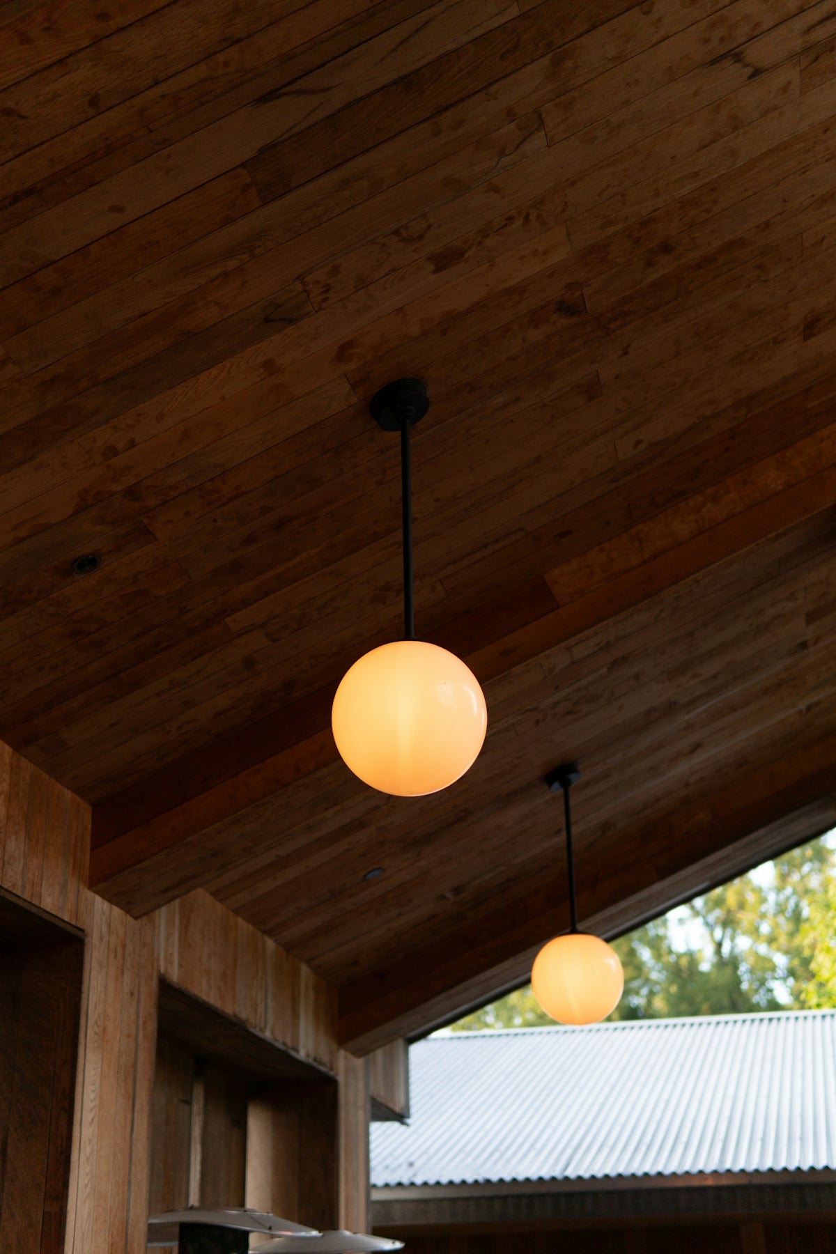 Two glowing spherical lamps hang from a wooden ceiling.