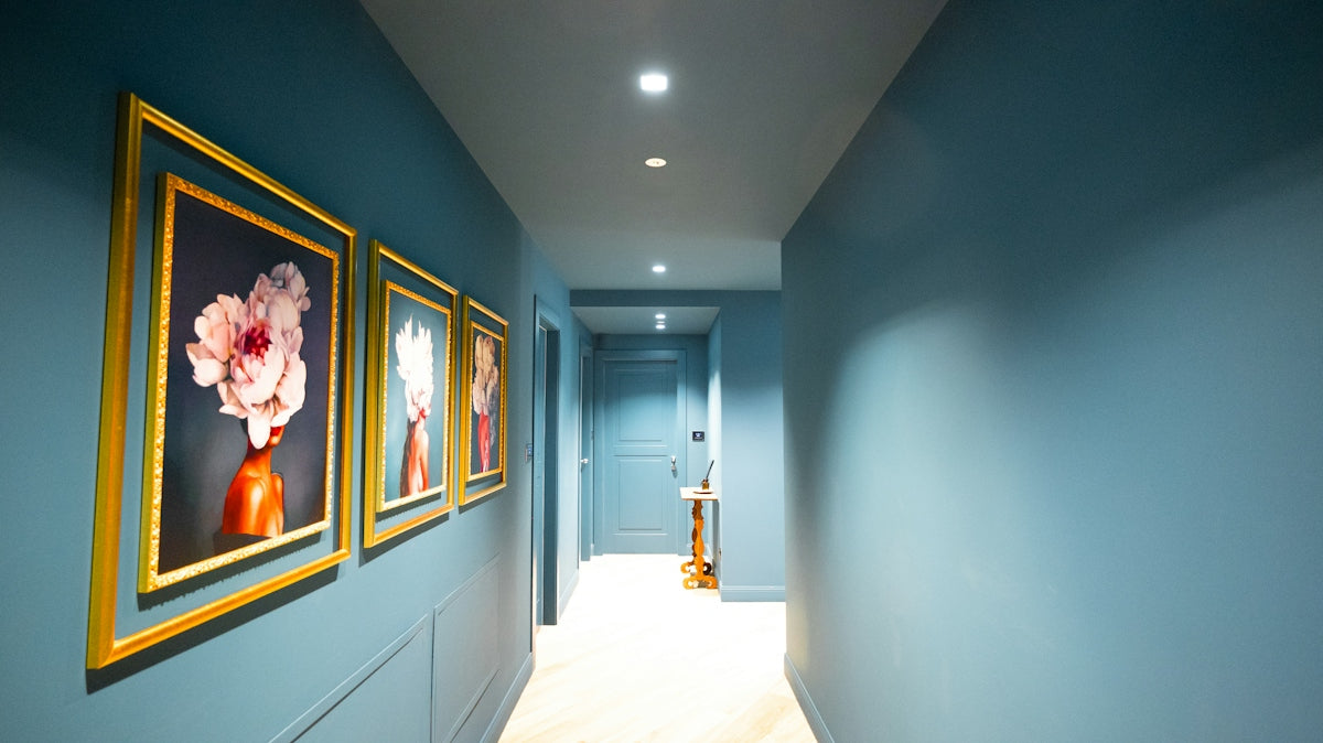 Hallway with blue walls and framed floral artwork.