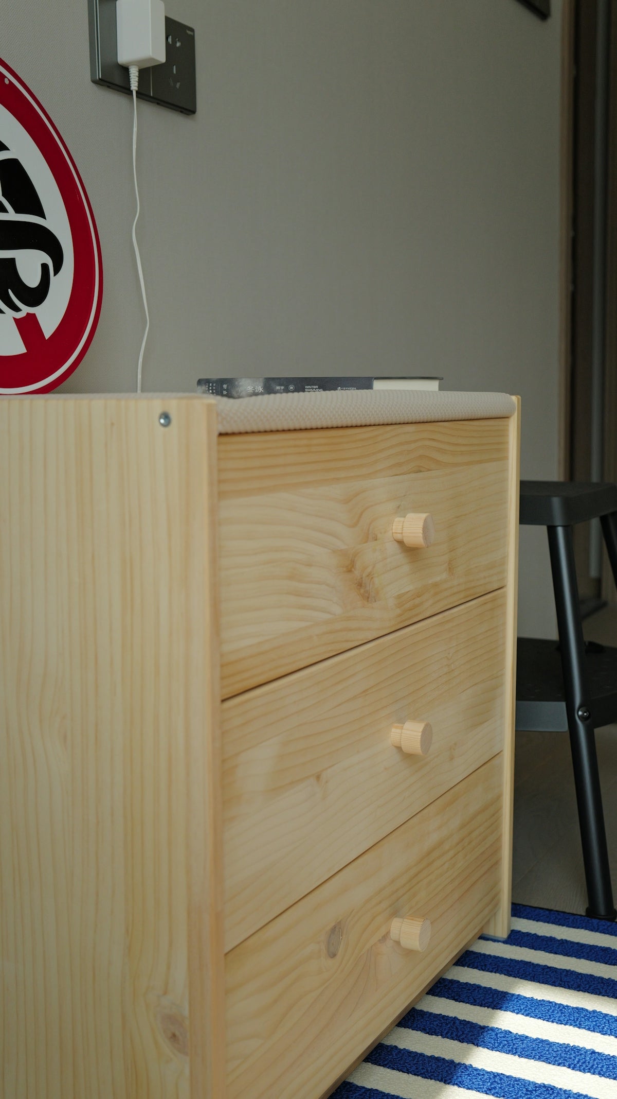 A light wood dresser with three drawers.