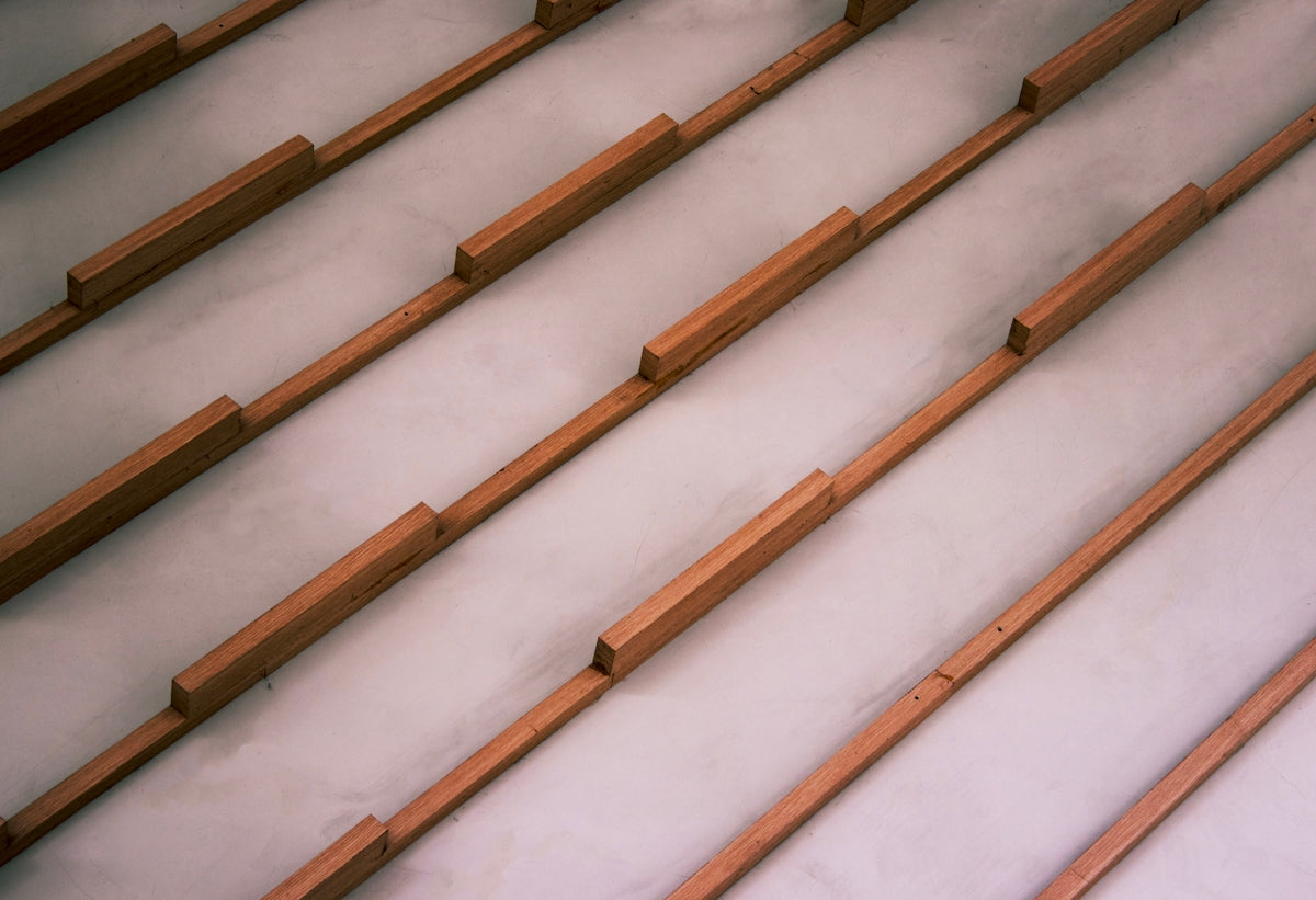 Wooden slats arranged diagonally on a light grey surface.