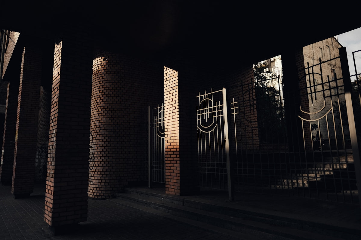 Ornate gates stand between brick pillars in shadow.