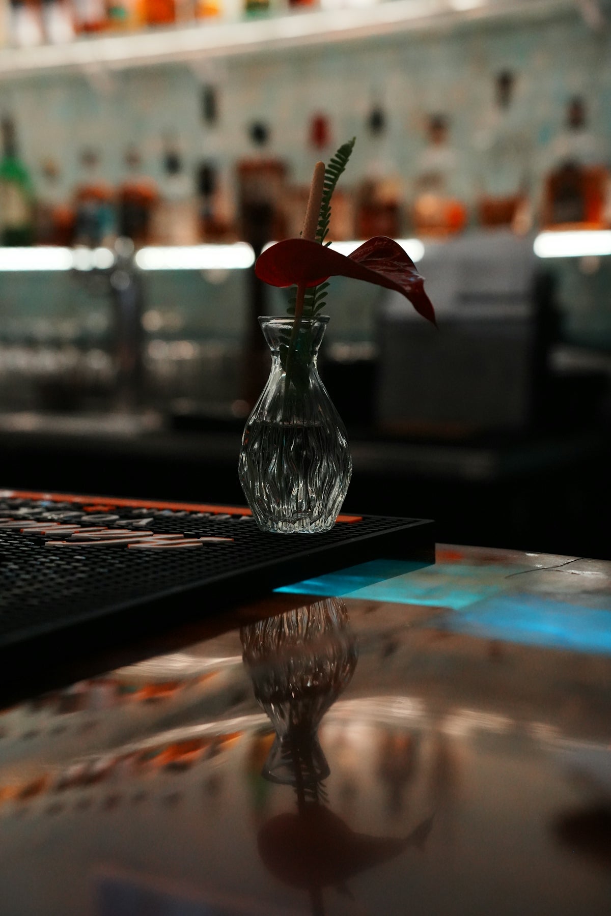 Small vase with red flower on bar counter