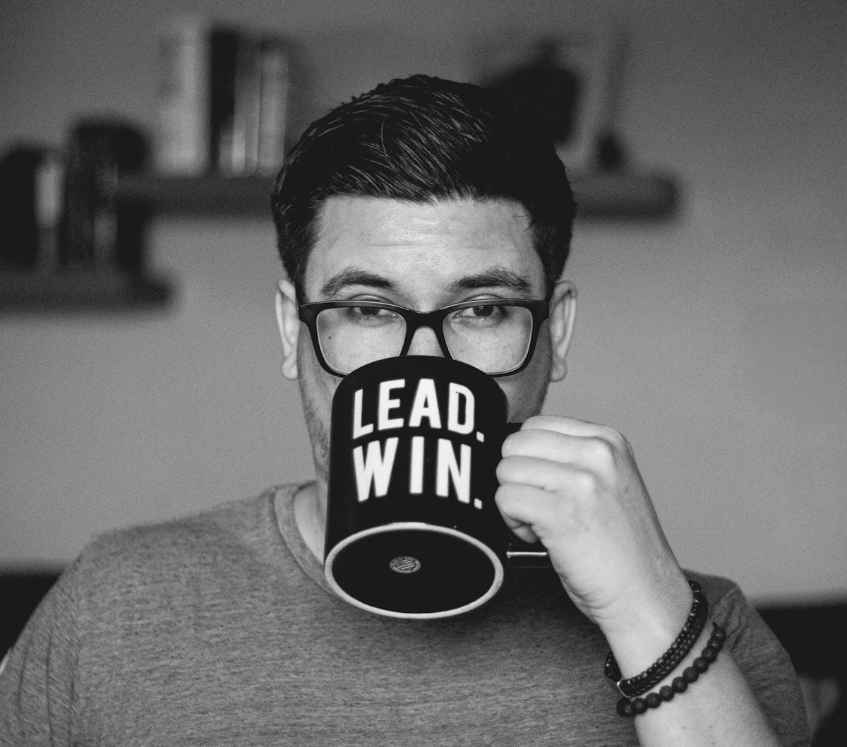 Man wearing glasses drinks from a mug