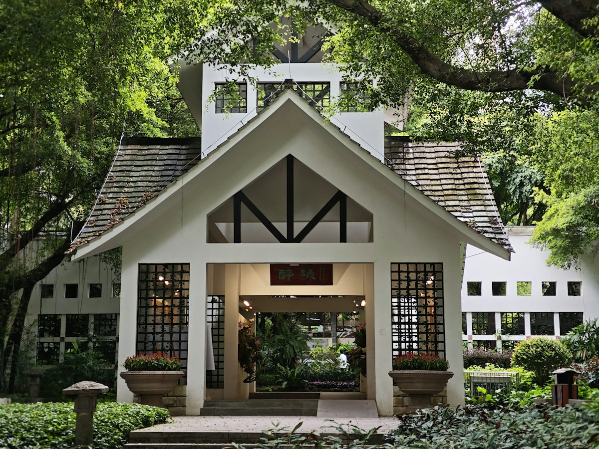 White building entrance surrounded by lush green trees