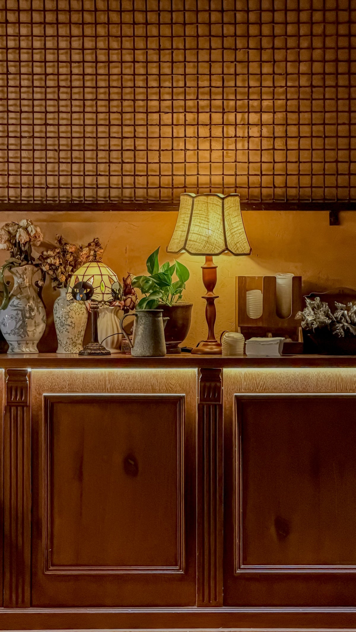 A dimly lit counter with decorative items and a lamp.