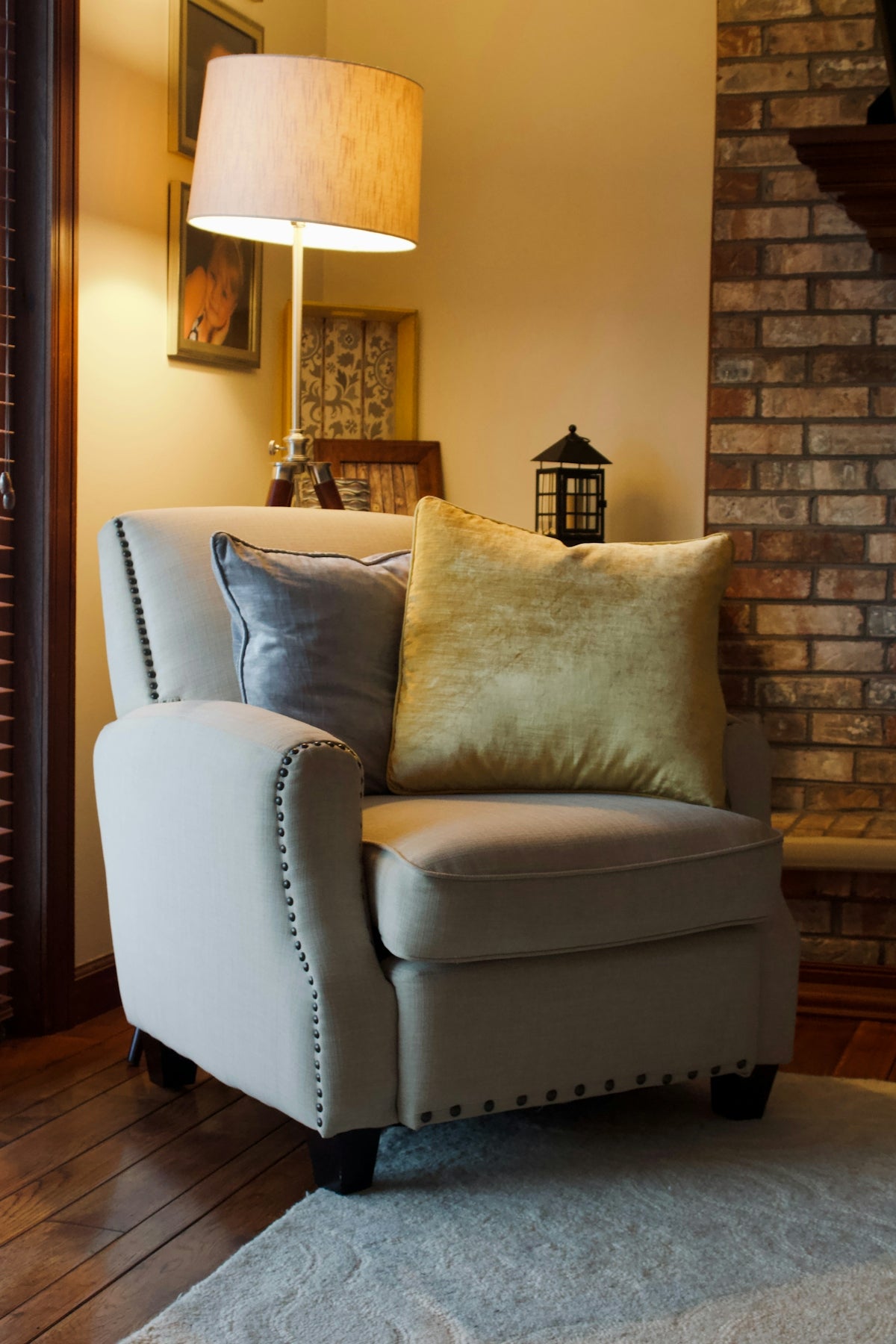 A comfortable armchair with decorative pillows and a lamp.