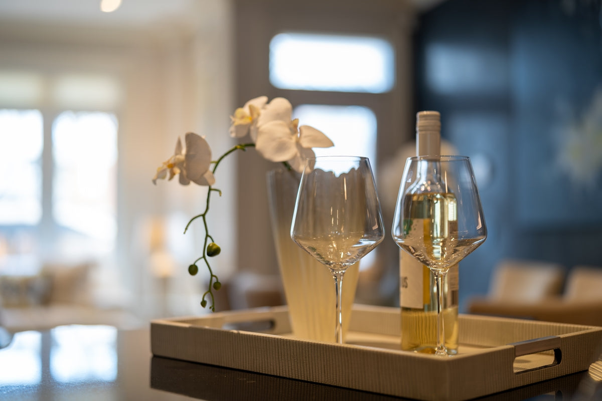 A bottle of wine and two glasses on a tray.