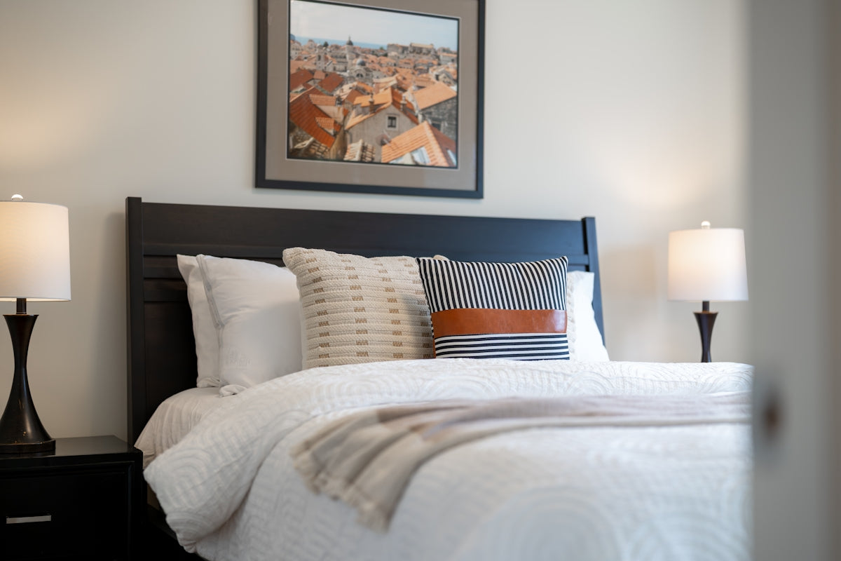 A neatly made bed with pillows and lamps.