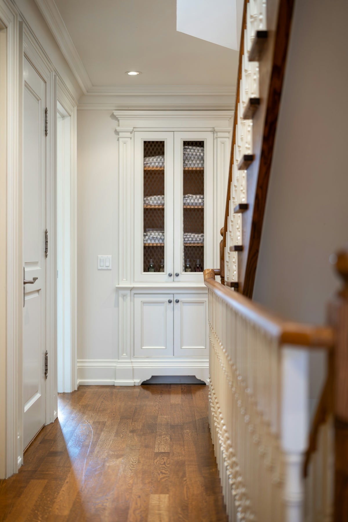 Hallway with built-in cabinet and wooden staircase railing