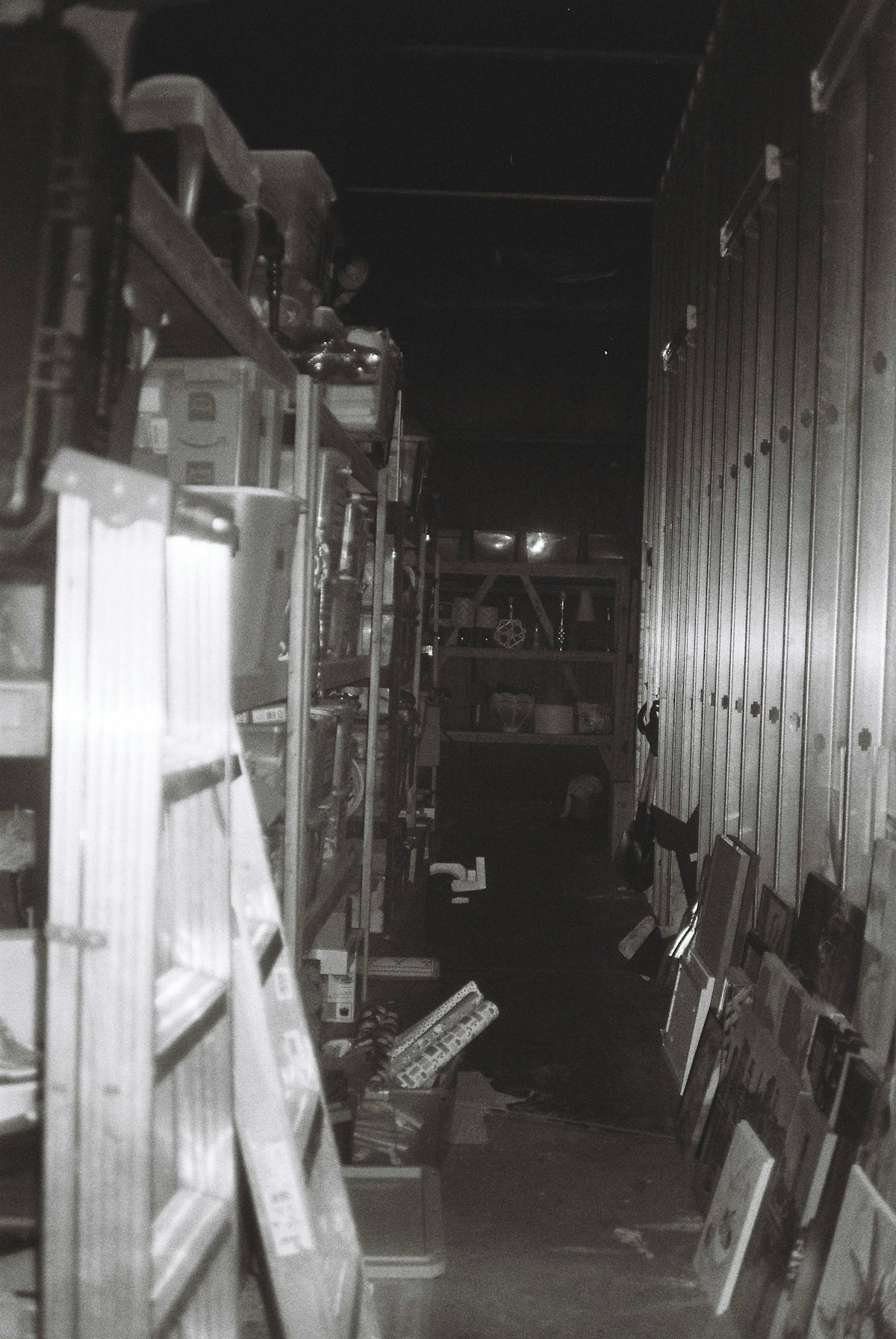 A dimly lit storage room with shelves and ladders