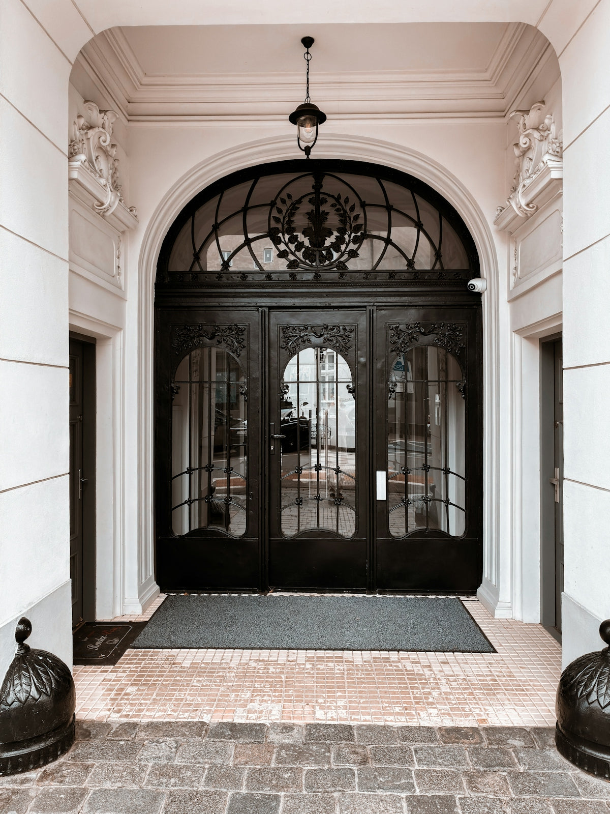 Ornate black double doors with glass panels and arched window
