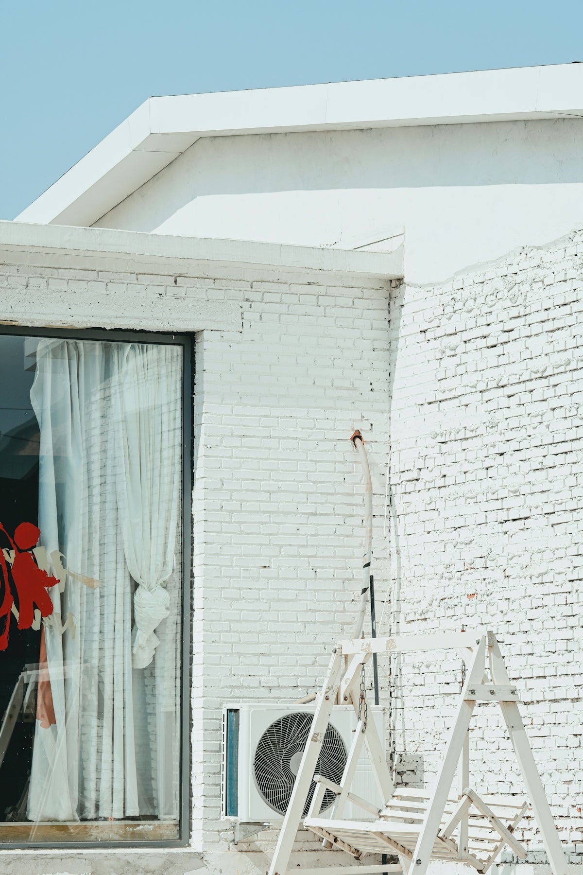 White brick building with a window and air conditioner.