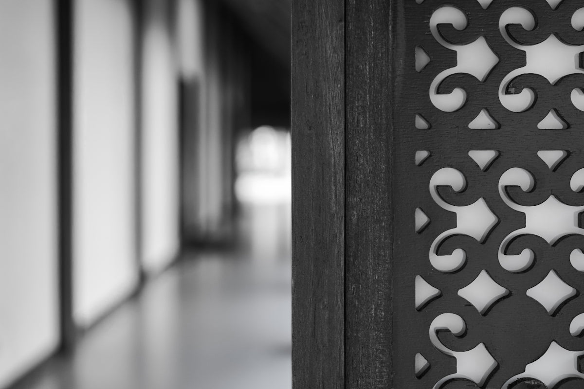 Close-up of a decorative wooden screen with hallway in background
