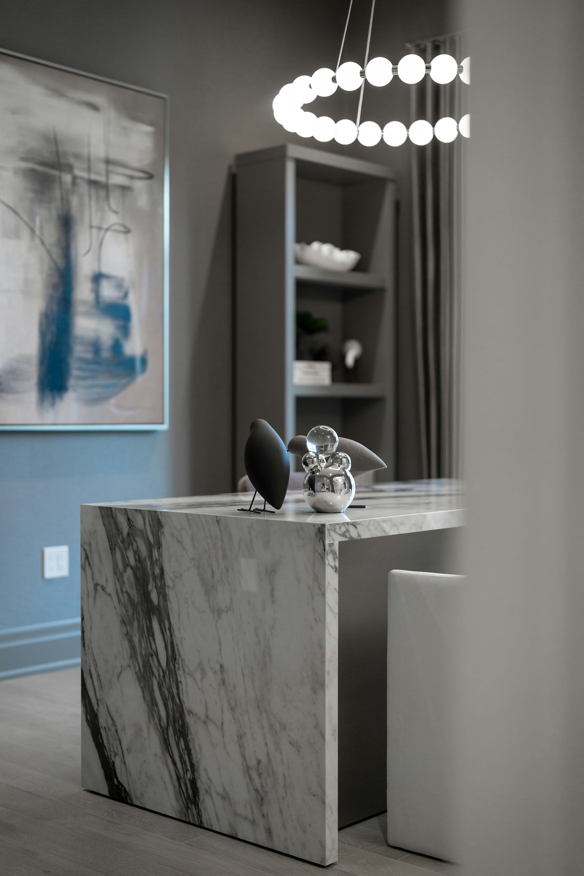 Contemporary office interior with a sleek marble desk and chandelier.