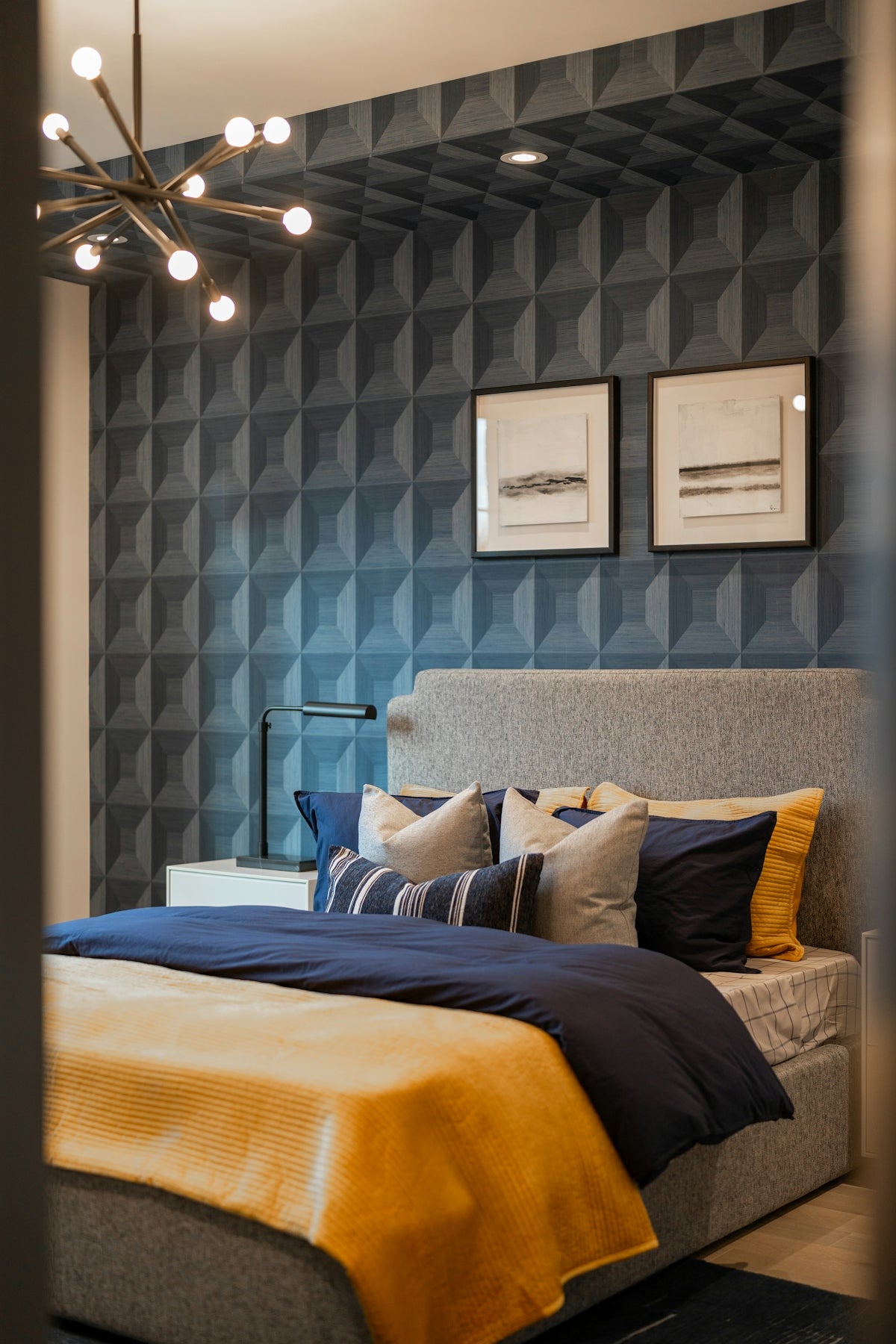 Modern bedroom with textured blue wallpaper and yellow accents.
